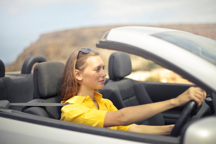 Woman In Yellow Shirt Driving A Silver Car