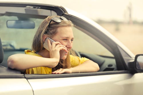 Donna Bionda In Maglietta Gialla Che Indossa Occhiali Da Sole Neri Che Tiene Smartphone D'argento