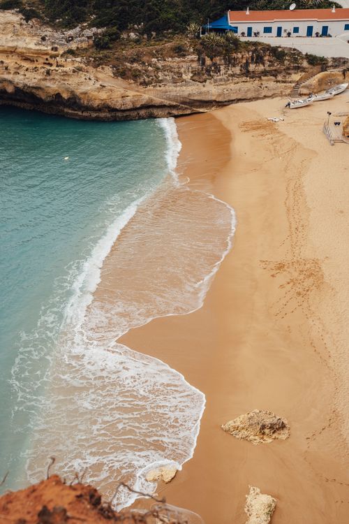 Free Stunning aerial view of a sandy beach and turquoise waves in Faro District, Portugal. Stock Photo