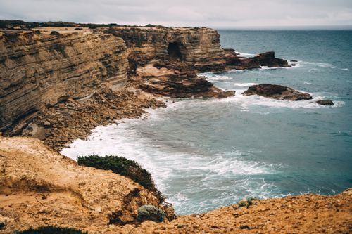 Free Coastal cliffs and ocean waves in the Faro District, Portugal, showcasing natural beauty. Stock Photo