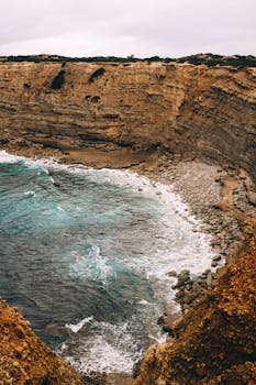 Dramatic cliffs and ocean waves in Faro District, showcasing Portugal's rugged coastline.