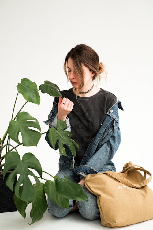 Free A Woman Sitting on the Floor while Looking an Indoor Plant Stock Photo
