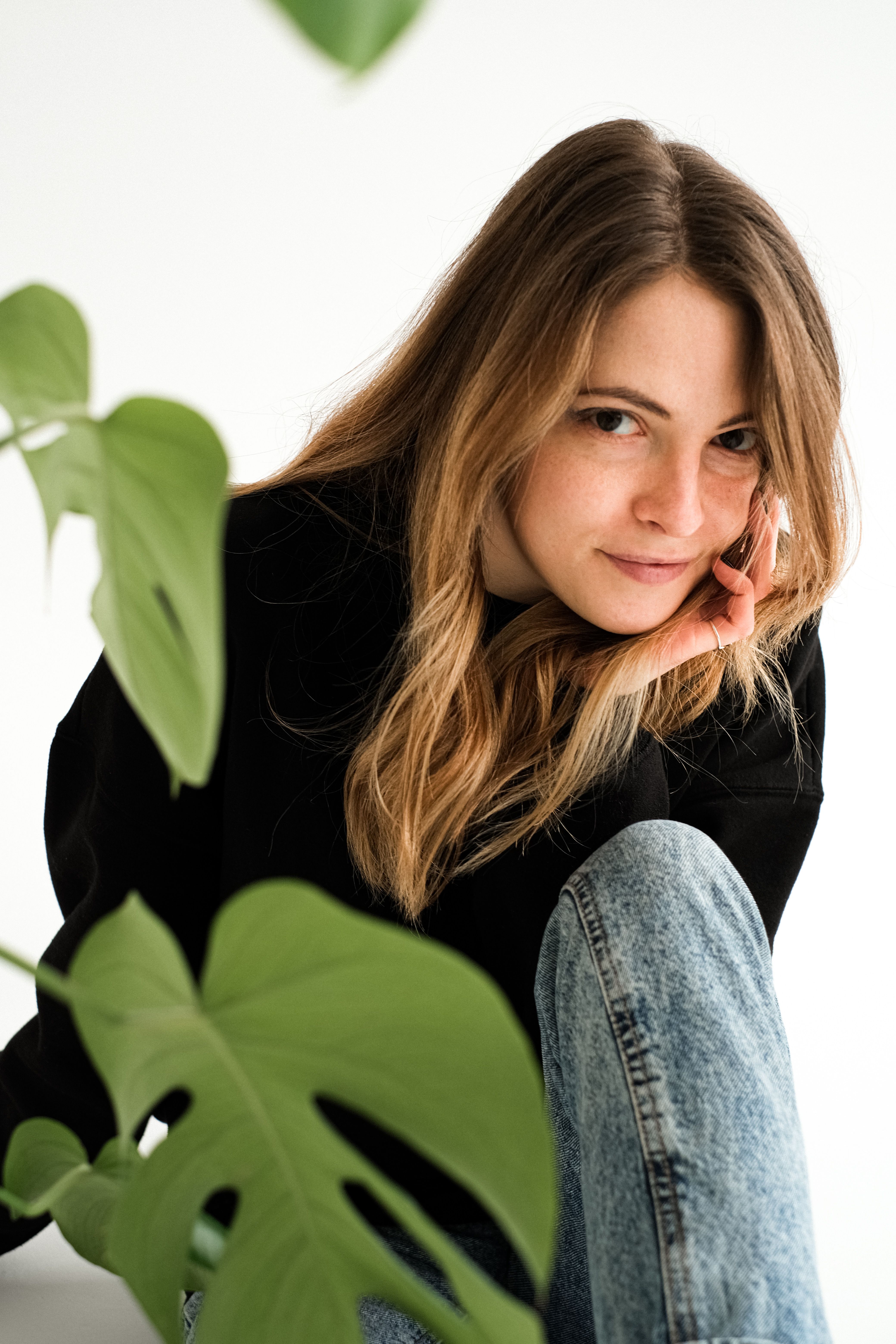 Fashionable woman in jeans posing with greenery, capturing a modern and natural vibe.