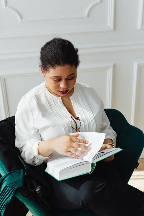 Free A woman reads a book in a relaxed indoor setting, promoting learning and tranquility. Stock Photo
