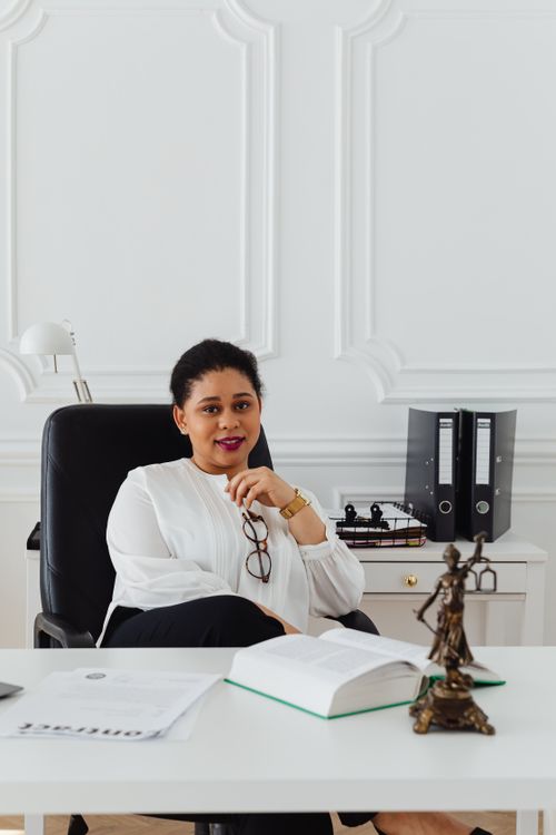 Free Professional woman sitting at desk in a stylish office, exuding confidence and leadership. Stock Photo