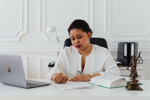 Free African American woman lawyer signing documents at a desk, symbolizing professionalism. Stock Photo