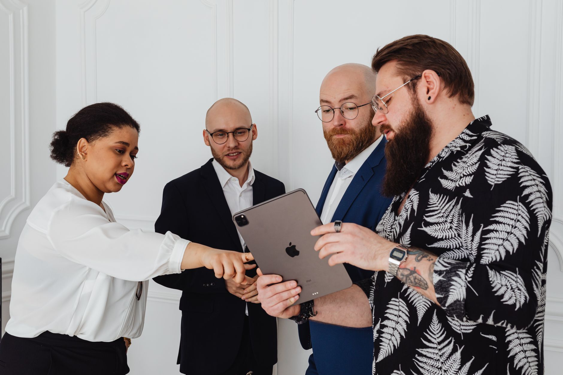 A group of diverse professionals discussing a project using a tablet in a modern office setting.