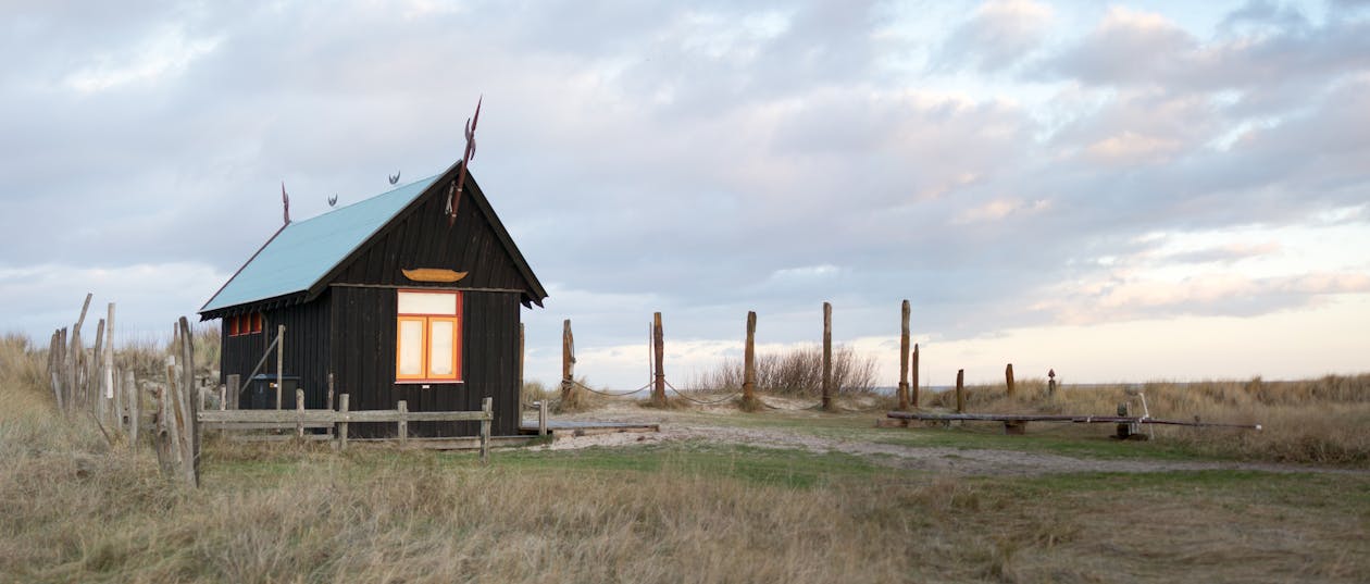 草に囲まれたフェンスのある木造の小屋