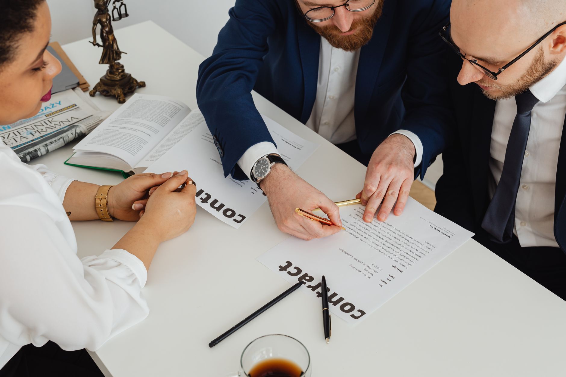 Business professionals engaged in contract review at a modern office desk. (Photo by https://kaboompics.com/ on Pexels)