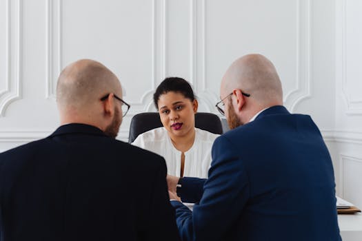A diverse group of business professionals engaged in a discussion in a modern office setting.