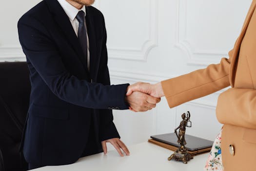 Two business professionals shaking hands in an office, showcasing agreement.
