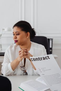 Professional woman in office attentively reading a contract document, conveying workplace focus.