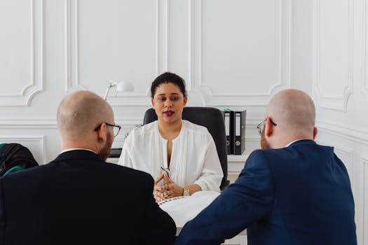 A woman leading a meeting with two colleagues in a modern office environment.