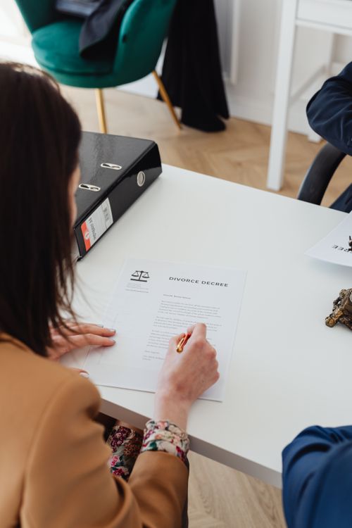 Free Over the shoulder view of a person signing a divorce decree at a desk in an office. Stock Photo