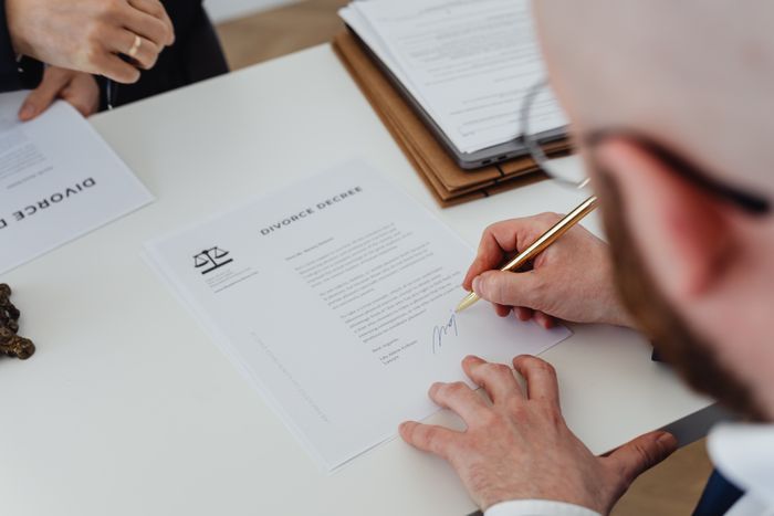 Contract paperwork being signed at a desk, photo by Kaboompics on Pexels