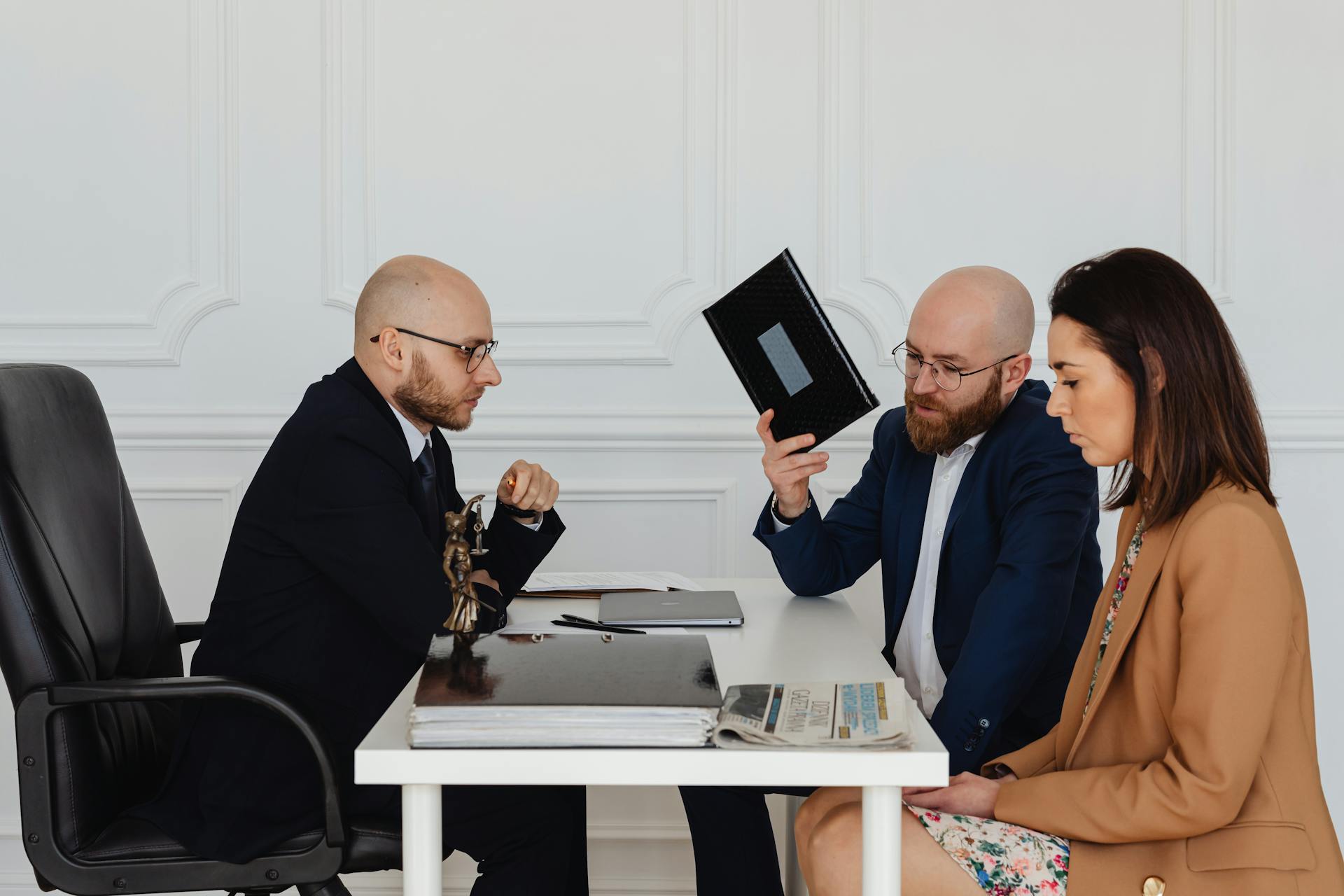 A couple in a legal consultation with a lawyer at an office desk.