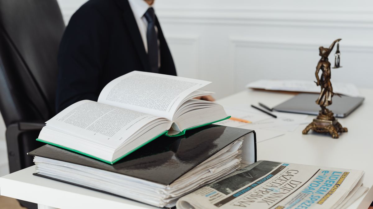 A lawyer sitting at a desk with legal books, documents, and a newspaper, embodying professionalism.