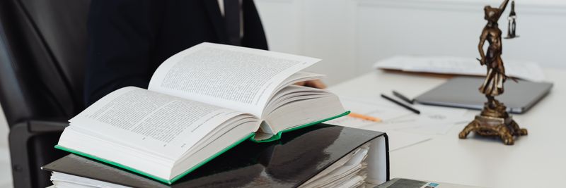 A lawyer sitting at a desk with legal books, documents, and a newspaper, embodying professionalism.