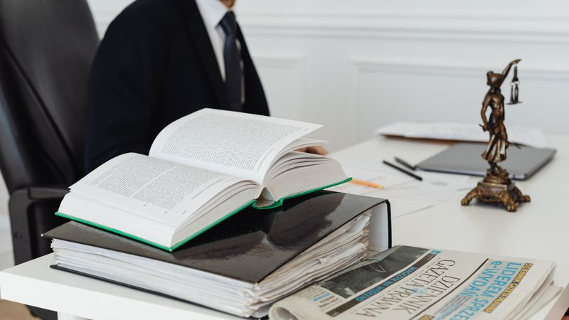 A lawyer sitting at a desk with legal books, documents, and a newspaper, embodying professionalism.