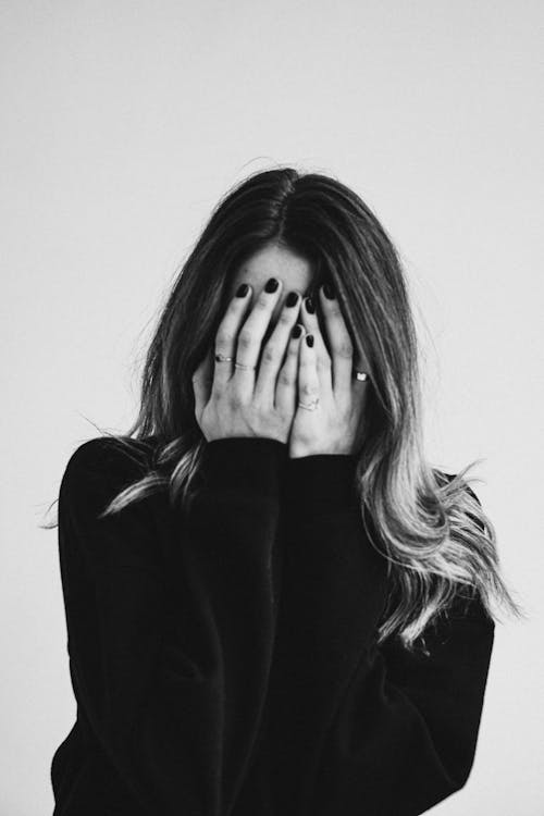 Grayscale Photo of a Woman Covering Her Face