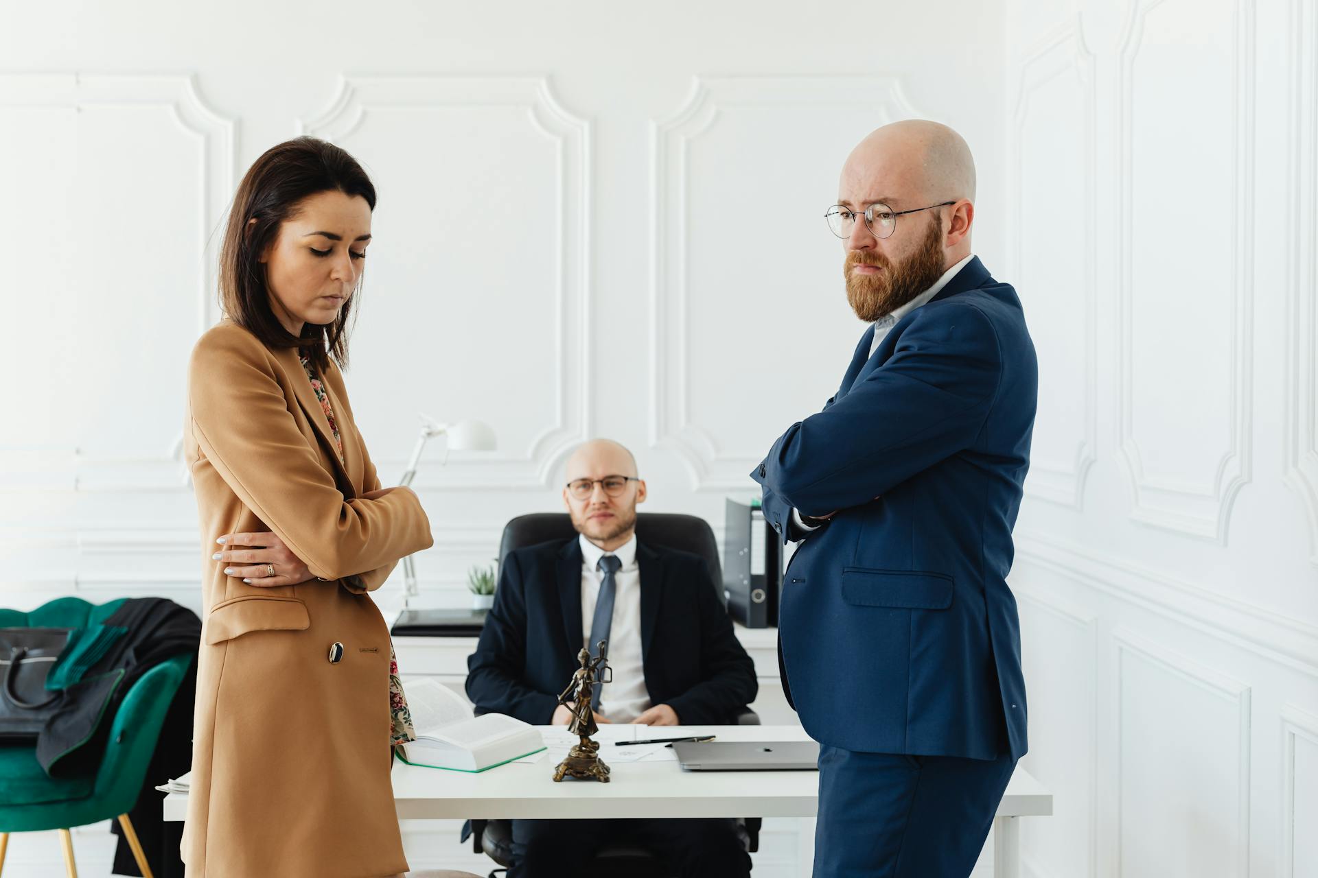 A couple in corporate attire seeks mediation during a business disagreement in an office setting.