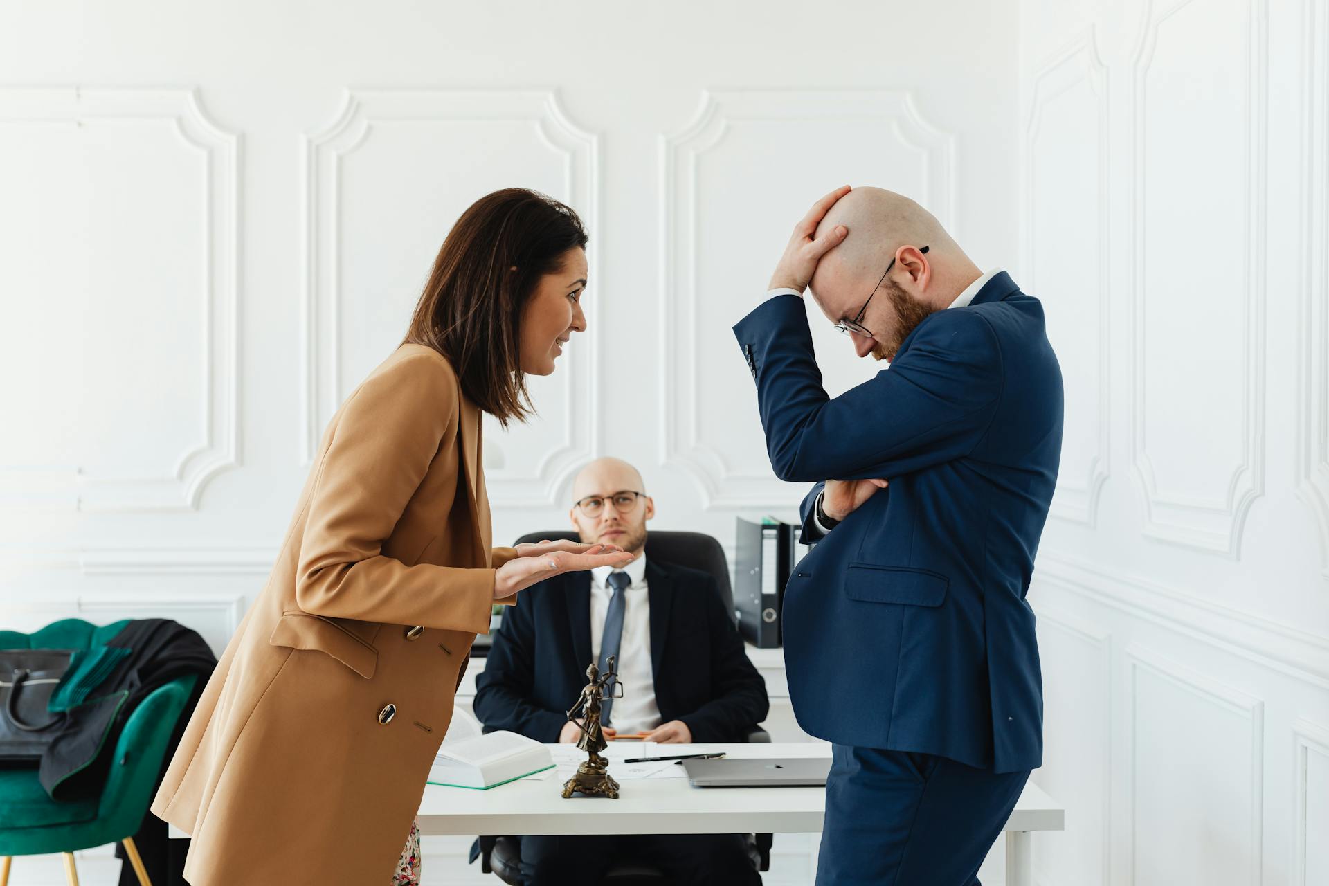 A couple having a heated argument in a law office with their attorney observing.