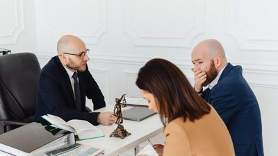 Consulta jurídica seria con tres personas en una oficina, sobre testigos testamento Chile