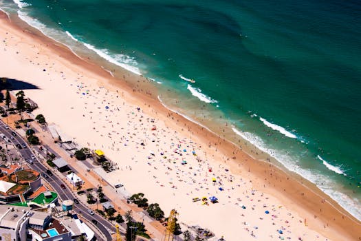 Stunning aerial view of a crowded tropical beach with vibrant umbrellas on a sunny day.