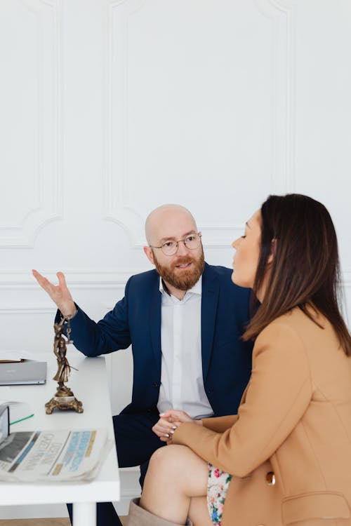 Free A Couple Sitting at a Desk with a Lady Justice Statue Stock Photo