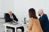 Three adults in a formal business meeting discussing legal matters in an office.