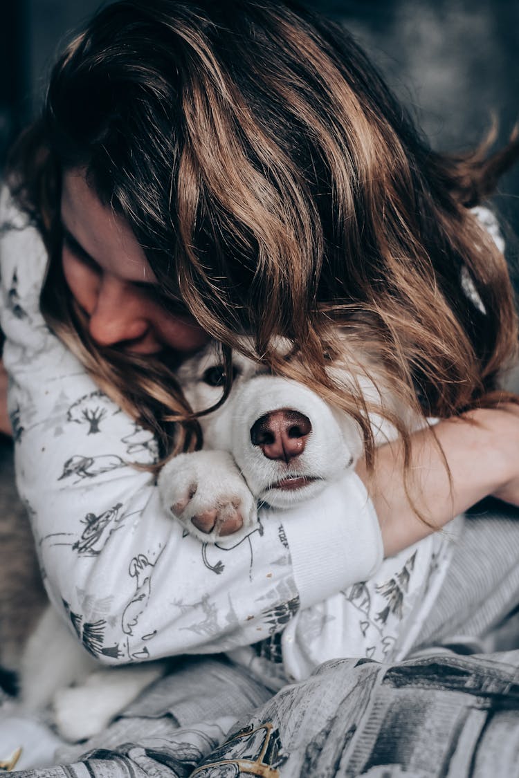 A Person With Long Wavy Hair Hugging A Dog