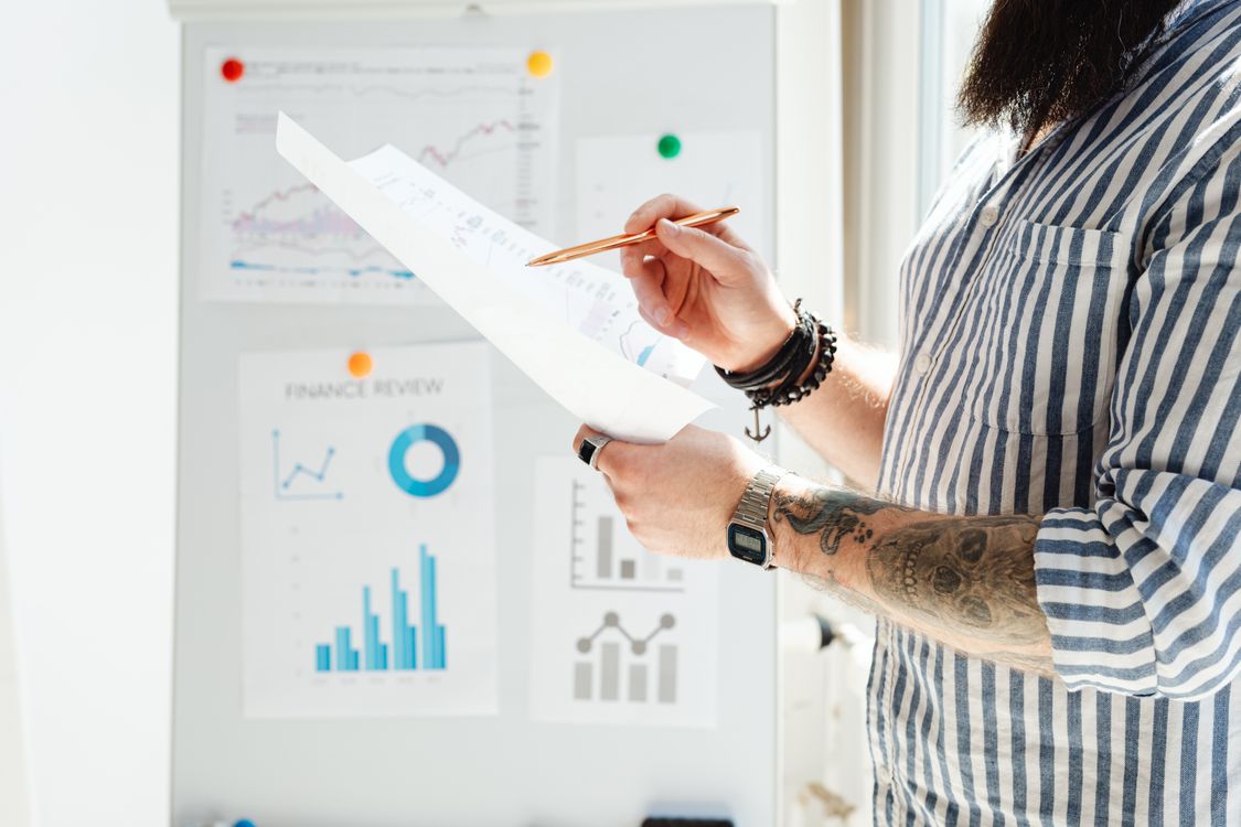 Free Professional reviewing financial graphs and documents in a bright office setting. Stock Photo Free Professional reviewing financial graphs and documents in a bright office setting. Stock Photo