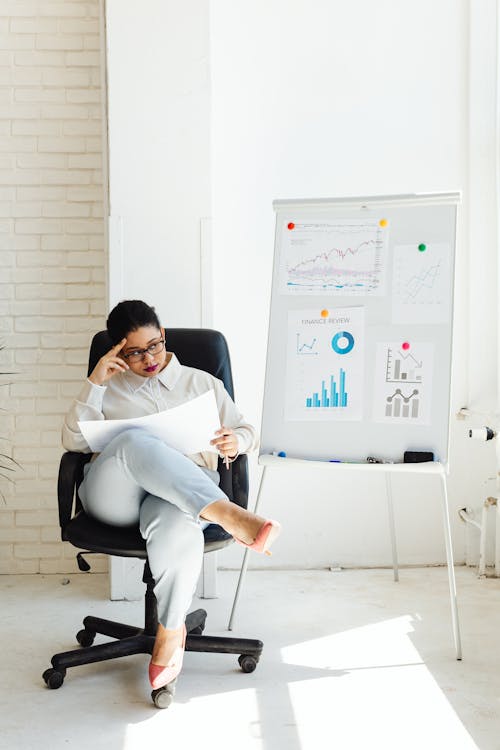 Free Woman in White Long Sleeve Shirt and White Pants Sitting on Black Chair Stock Photo