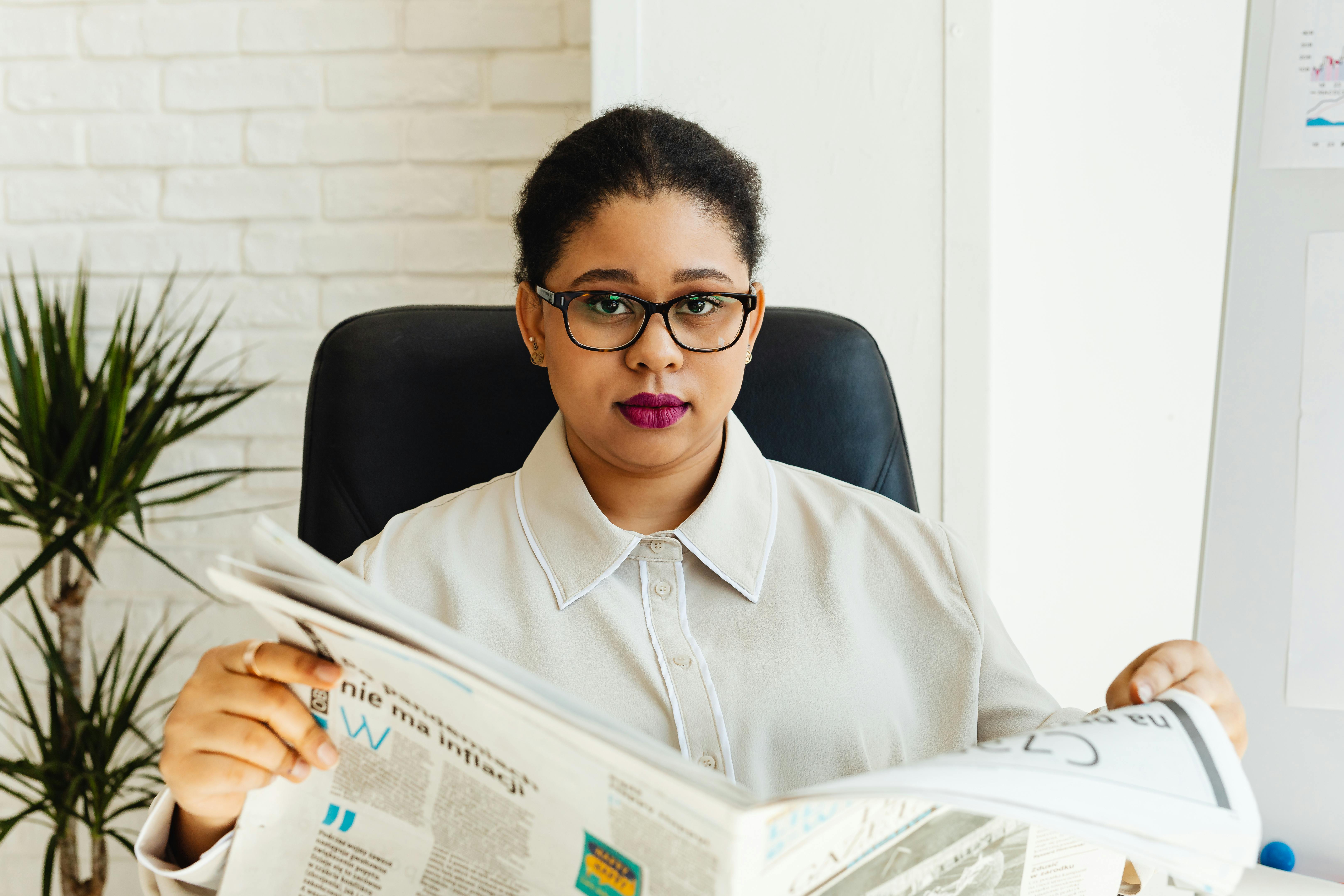 a woman wearing eyeglasses holding a newspaper