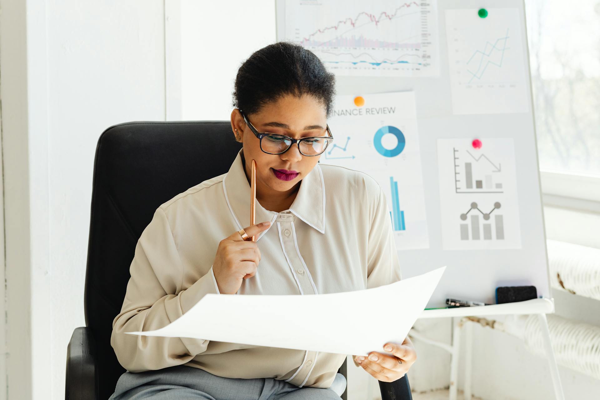 Businesswoman in glasses analyzing financial documents at her office desk.