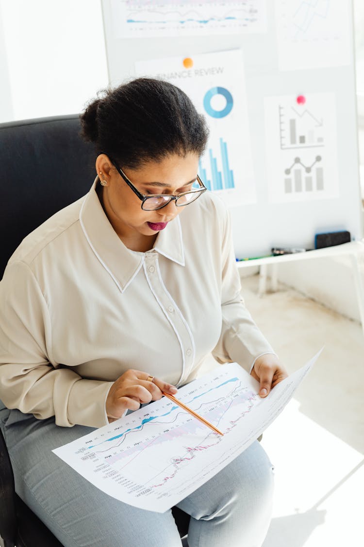 A Woman Sitting On The Chair While Reviewing A Chart