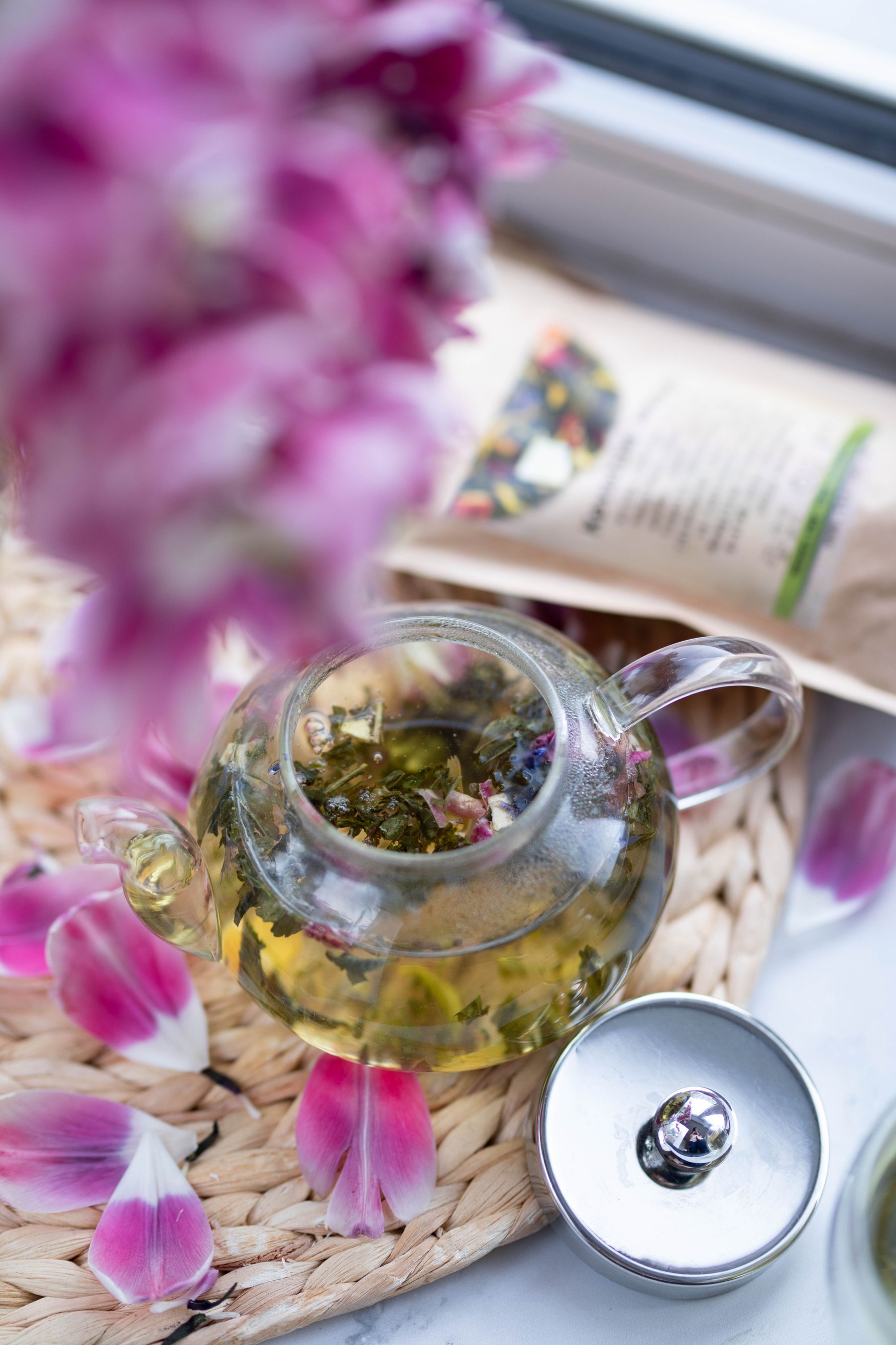 Herbal tea brewing in a glass teapot near flowers Herbal tea brewing in a glass teapot near flowers