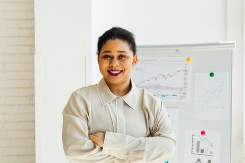 Free Businesswoman standing confidently with charts in modern office setting. Stock Photo