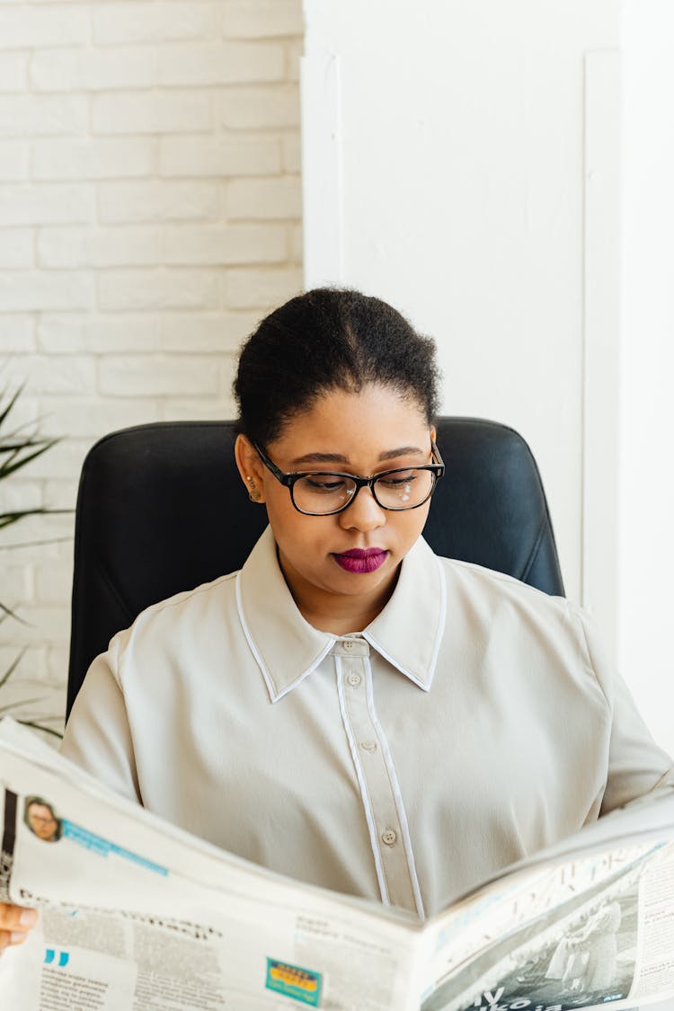 A Woman In Corporate Attire Reading The Newspaper