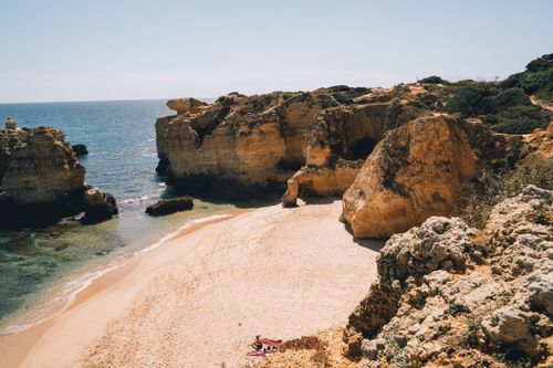 Free Explore the stunning golden cliffs and serene beach of Algarve's coast in Portugal. Stock Photo