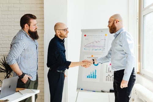 Free Three business colleagues engage in a productive meeting, exchanging ideas with data charts. Stock Photo