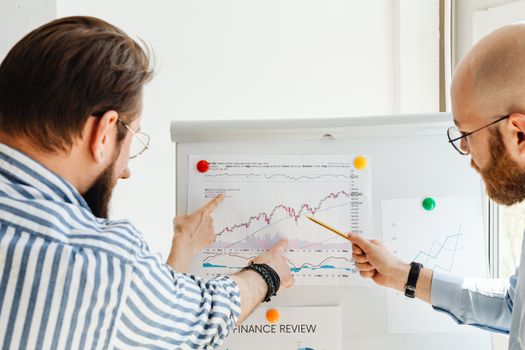 Two business professionals analyzing financial charts during a daytime meeting.