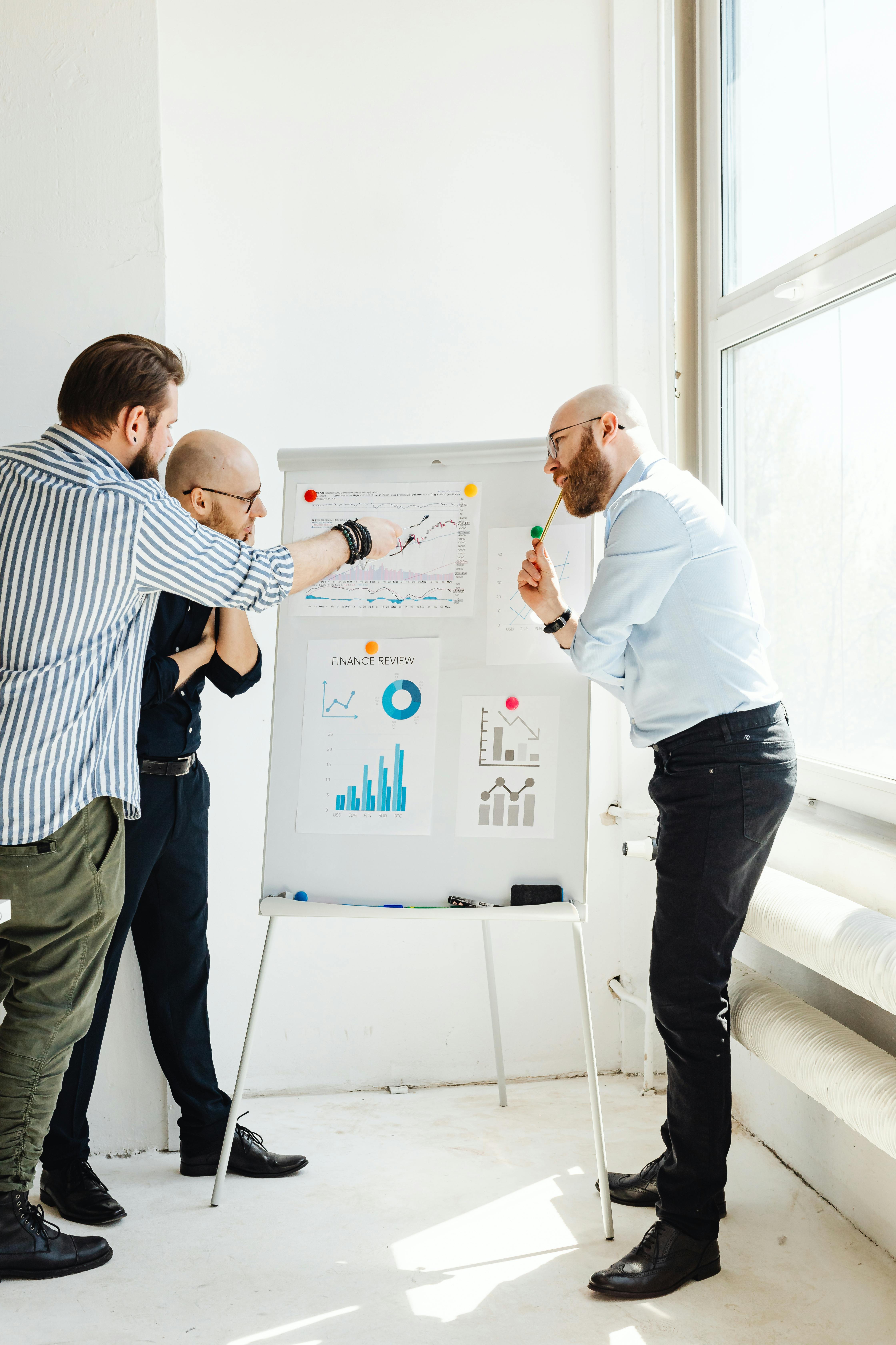 three men discussing stock review charts