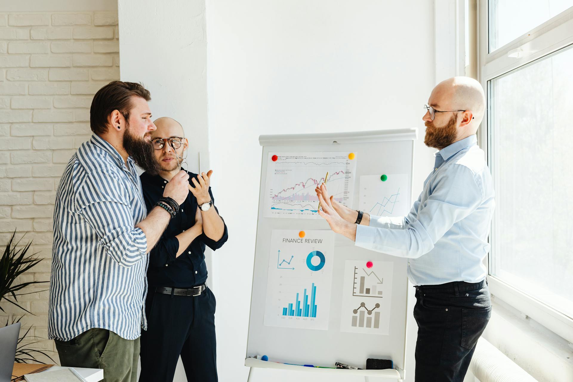 Three professionals discussing financial charts and graphs during a business meeting.