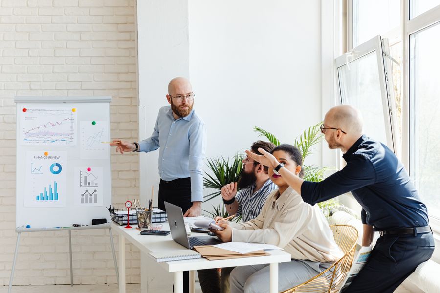 A team standing at a whiteboard covered in charts, discussing results during a review meeting.