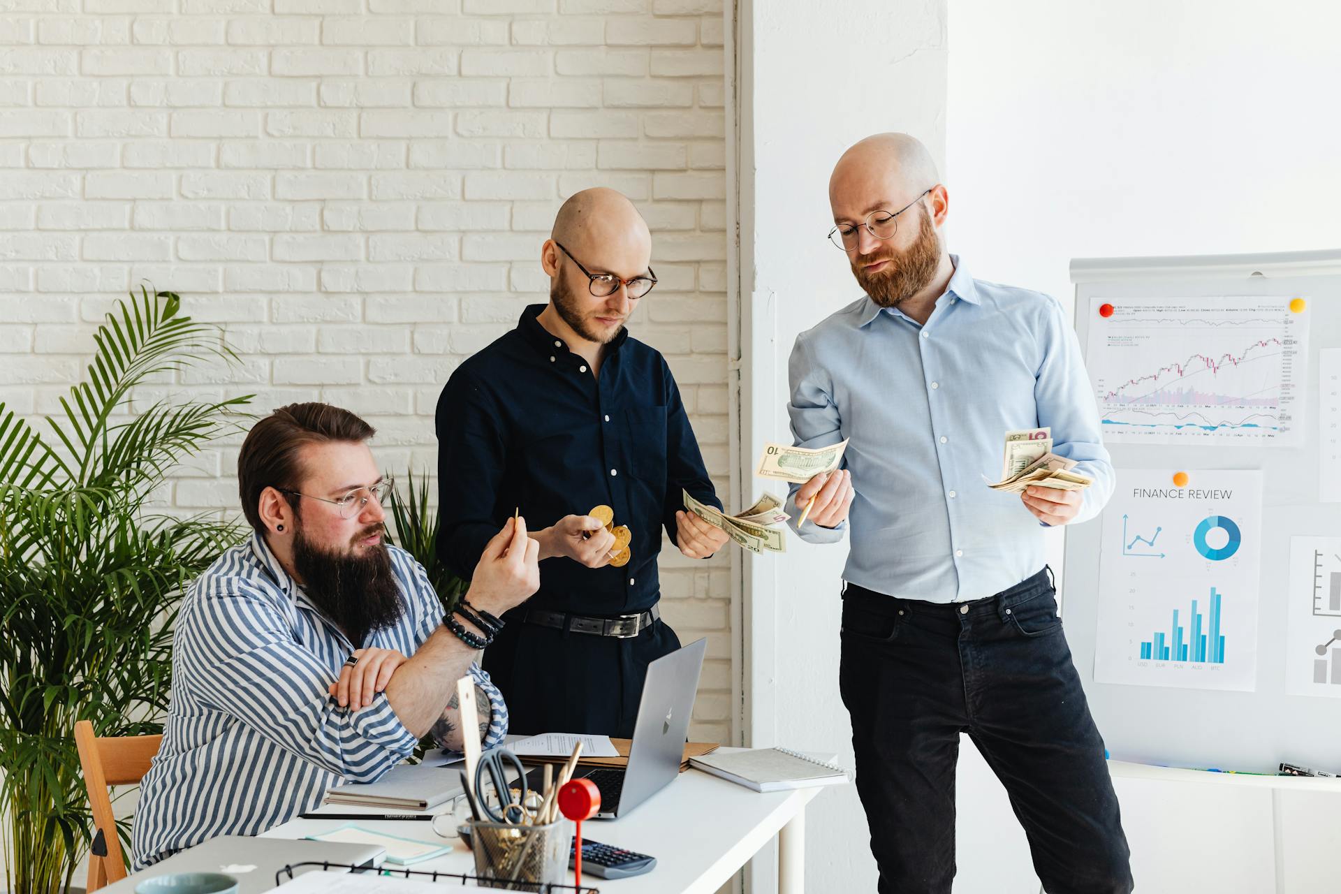 Three business colleagues discussing financial strategies and reviewing charts in a modern office.