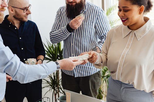 Business professionals exchanging money in a casual office setting.