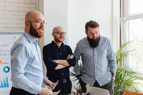 Free Three colleagues engaged in a positive office meeting, discussing business strategies. Stock Photo
