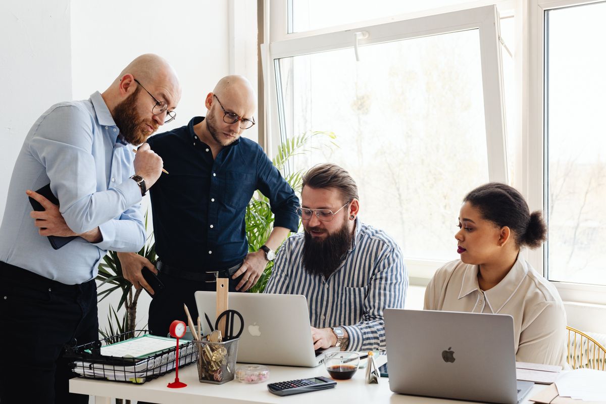 A diverse community of developers collaborating around a laptop