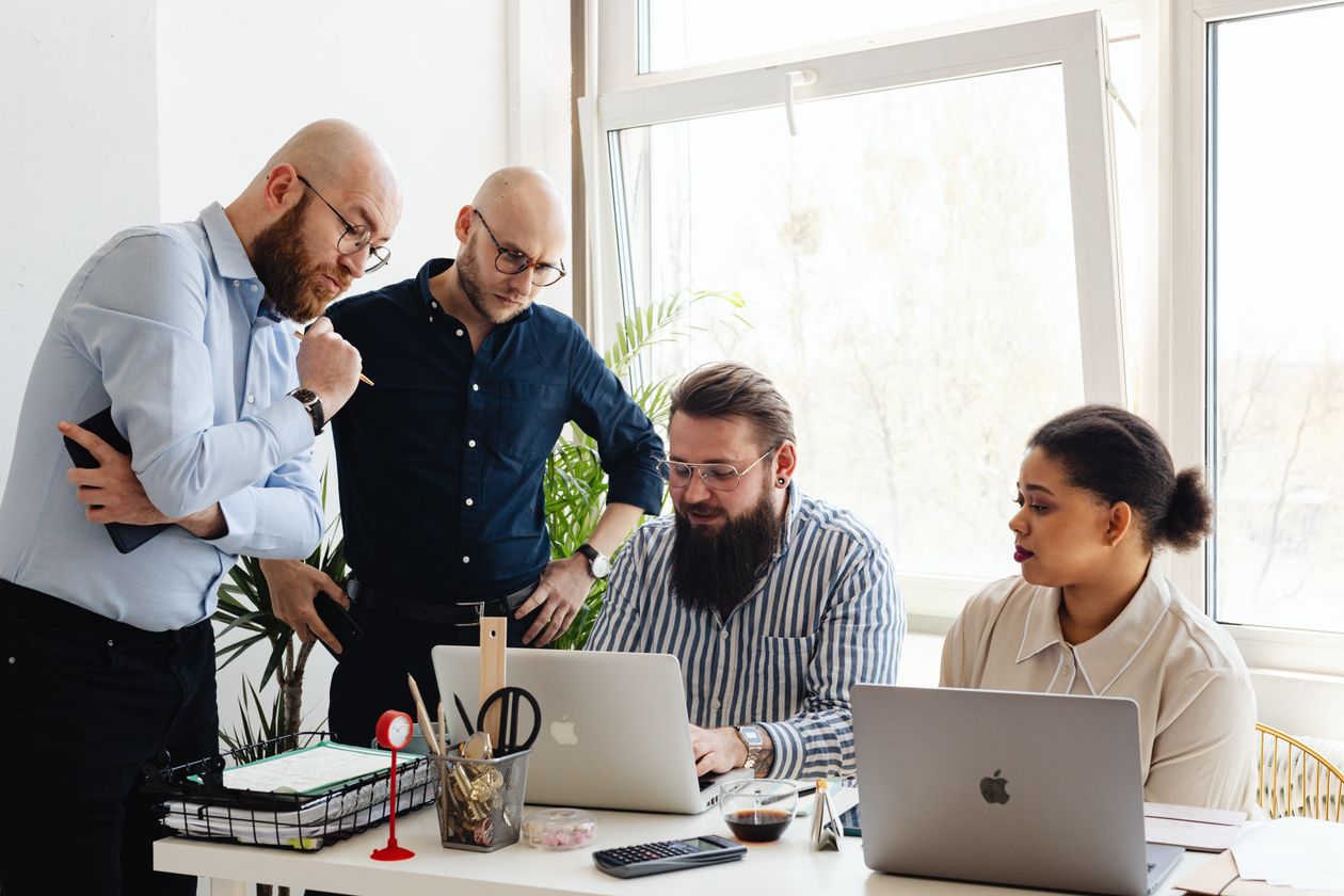 Marketing agency team reviewing social media content for multiple client accounts on a laptop